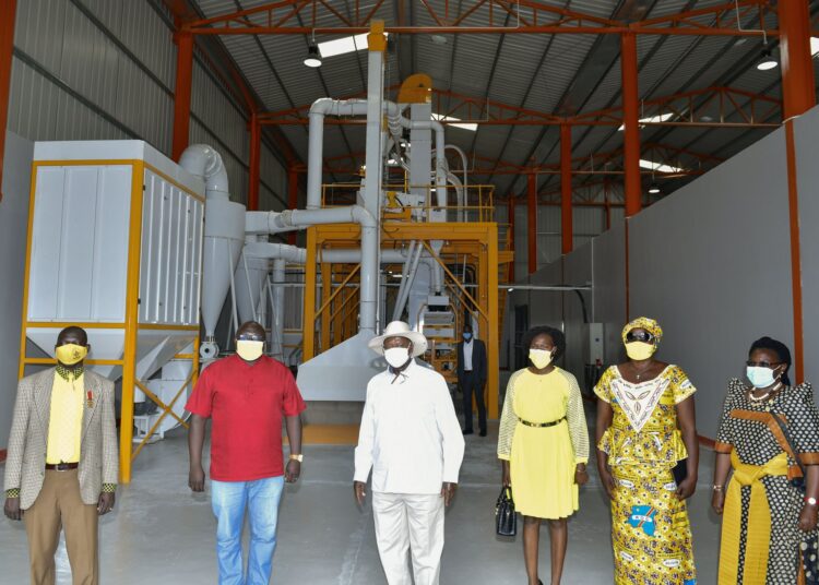 Eng. Joel Aita (in red), President Museveni (to his immediate right), Minister Evelyn Anite, and other officials after the Joadah Consult founder had taken the head of state on a tour of his value addition processing factory set to process 250,000kg of cereals per day at full capacity.